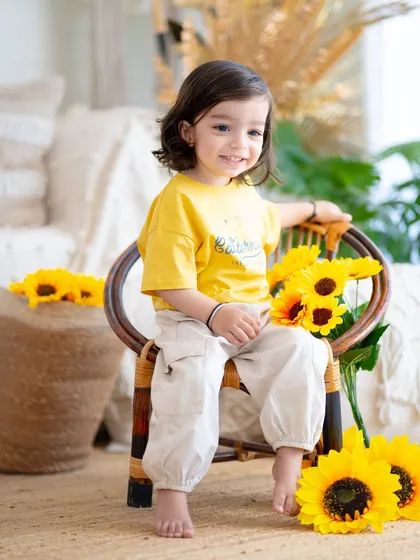 A bright and sunny portrait with sunflowers. This little one's happy smile is as bright as the flowers beside her.