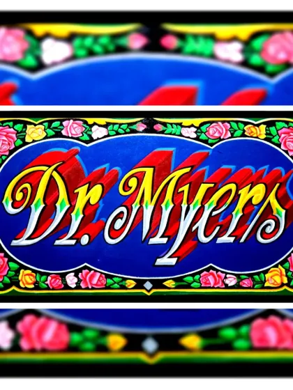 A nameplate for "Dr. Myers," framed with a beautiful border of hand-painted roses, a common element in truck art.