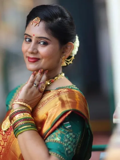 A classic South Indian traditional look for Pavithra's son's Upanayana ceremony. The look features a bright red lip, defined eyes, and a traditional hairstyle with fresh flowers, perfectly complementing her silk saree and gold jewelry.