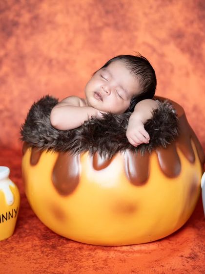 This little one is sleeping in a 'hunny' pot, a sweet and creative concept for a newborn shoot.