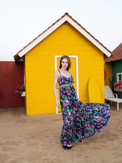 A shot capturing the movement of a long floral dress from the Tangerine Tiger collection, set against a beach hut backdrop.