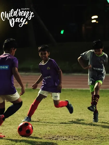 Three of our youngest players enjoying a game under the lights. This is what grassroots football is all about: fun, friends, and a football.
