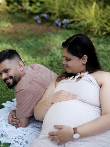 A candid moment of a couple relaxing on a picnic blanket in a lush park, sharing a happy glance.
