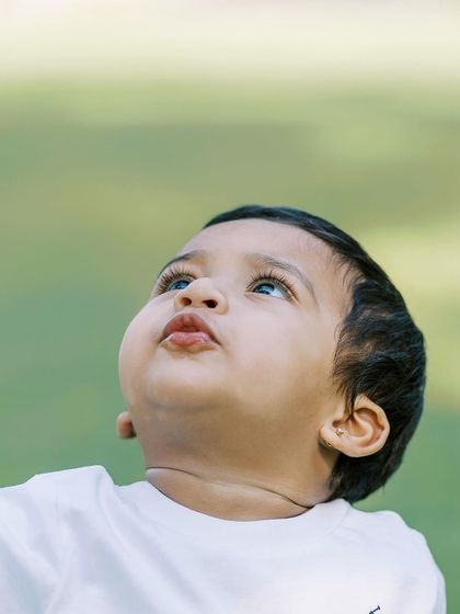 A close-up of a baby boy looking up at the sky, his long lashes and chubby cheeks perfectly captured.