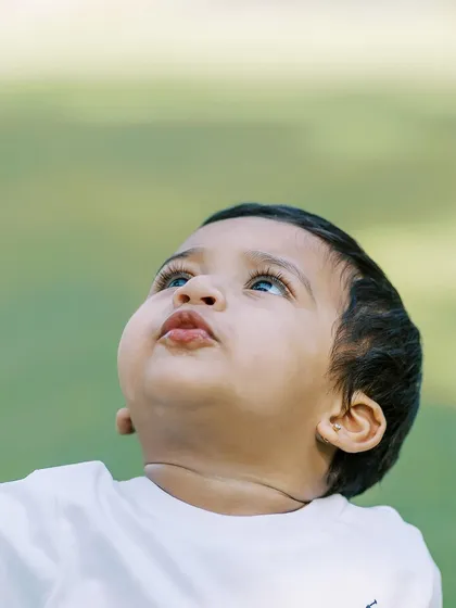 A close-up of a baby boy looking up at the sky, his long lashes and chubby cheeks perfectly captured.