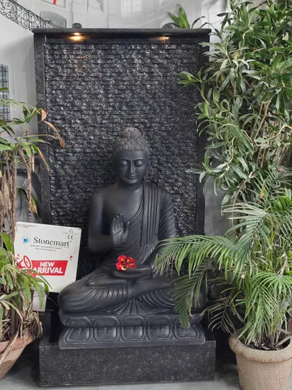 A full view of the black marble Buddha fountain, a unique and serene piece for large indoor spaces or gardens. The sound of the water cascading down the granite wall adds a tranquil element.