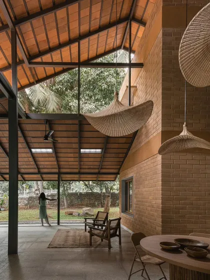 The double-height living space at Villa Maati showcases our use of volume and texture. The exposed brick walls and tiled roof are complemented by large woven pendant lights, creating a warm and inviting atmosphere that feels both grand and intimate.