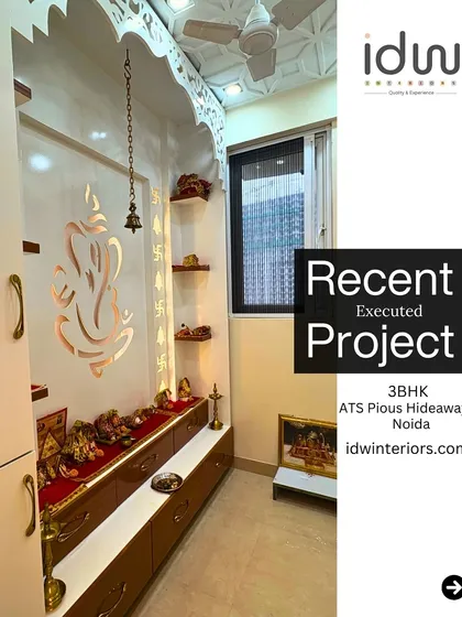 A dedicated pooja room with a large Ganesha motif cut into the back panel. The traditional arch design and warm lighting create a divine and peaceful atmosphere.