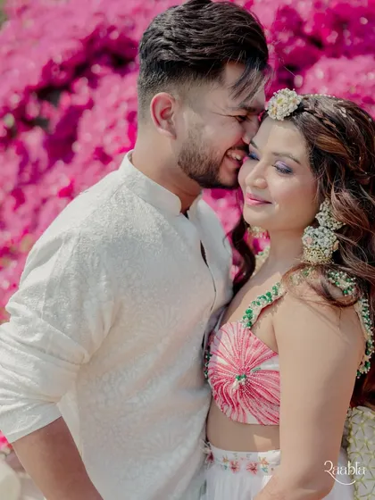 A sweet and tender moment between the couple against a backdrop of bright pink bougainvillea.