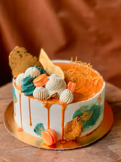 A side view of the artistic cake with macarons and a caramel drip.