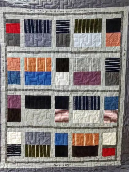 This modern memory quilt uses blocks of t-shirts and other clothing, arranged to look like a bookshelf, with custom embroidered messages.