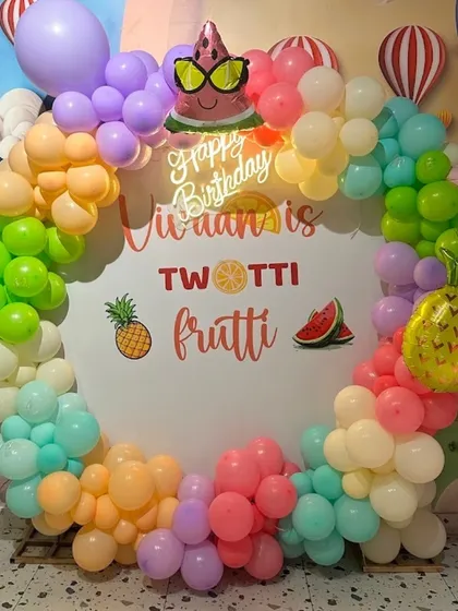 A sweet and colorful "Twotti Frutti" theme for a 2nd birthday, with a fruit-filled balloon wreath creating a perfect photo spot.