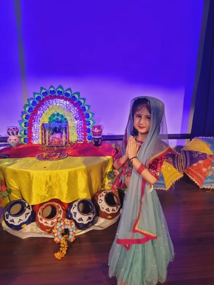 A young student dressed as a Gopi for Janmashtami stands before a beautifully decorated shrine. Our celebrations are visually rich and immersive, helping children connect with the stories and traditions of our festivals.