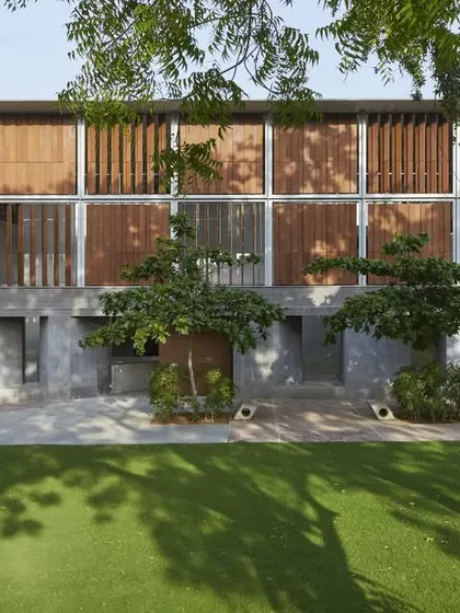 The facade of the Lilavati Lalbhai Library at CEPT University features operable wooden louvers. This system allows users to modulate the amount of natural light entering the building, providing thermal comfort and reducing energy consumption.