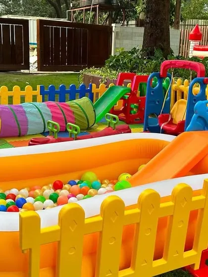 Another view of the outdoor setup, focusing on the inflatable ball pit with a slide. You can also see the crawl tunnel and part of the swing set.