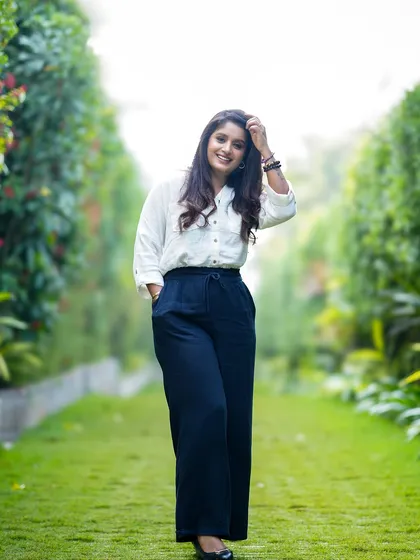 A full-length portrait of a woman enjoying a walk in a beautiful green space, looking happy and relaxed.