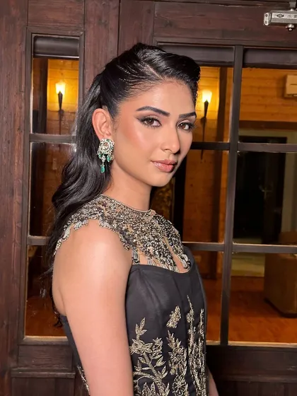 A look of understated elegance for an evening event. The makeup features a sharp wing and glowing skin, perfectly complementing the black and gold couture by Jade.