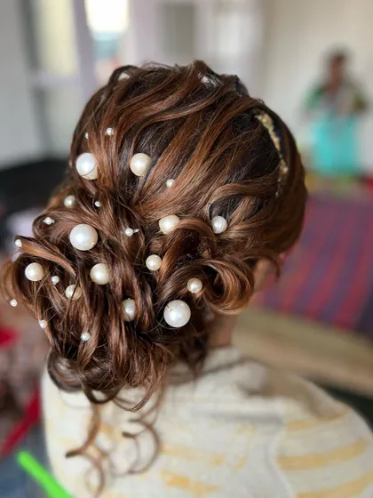 A close-up of the pearly messy bun, showing the beautiful interplay of light on the highlighted hair and the luminous pearls.