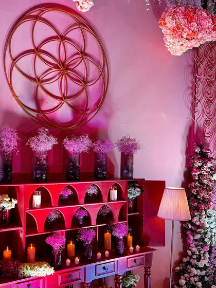 A beautifully styled console table at the 'Anant' wedding, featuring the Flower of Life symbol, abundant florals, and soft candlelight to create a welcoming and elegant atmosphere.
