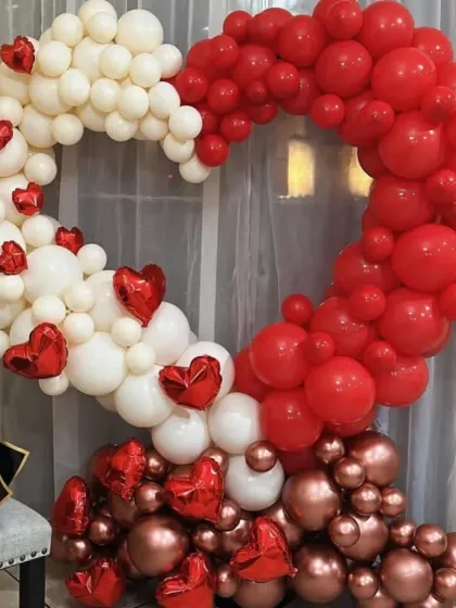 I love getting creative with balloons. This heart-shaped balloon arrangement uses a mix of red, white, and metallic rose gold balloons to create a beautiful and eye-catching photo backdrop for any romantic occasion.