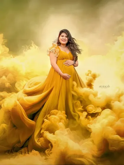 A truly artistic and dramatic portrait using colored smoke effects. The yellow gown appears to emerge from a golden cloud, creating a powerful and otherworldly image for a unique maternity shoot.