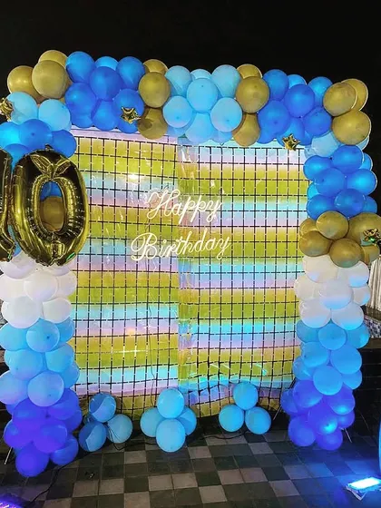 The complete poolside birthday setup, with a blue and gold balloon frame and a foil number '10'.