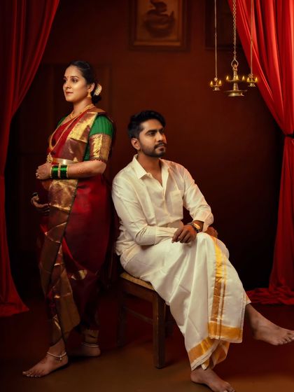 A powerful and artistic portrait of a couple in traditional attire, set against a rich, dramatic red curtain.