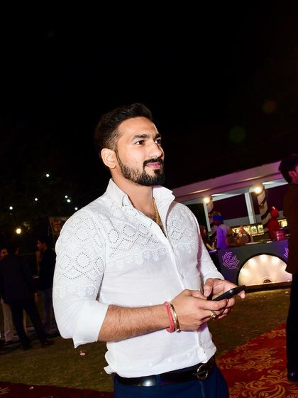 A candid shot of a client enjoying an evening event in his bespoke white embroidered shirt, showcasing how my designs blend seamlessly into moments of celebration.