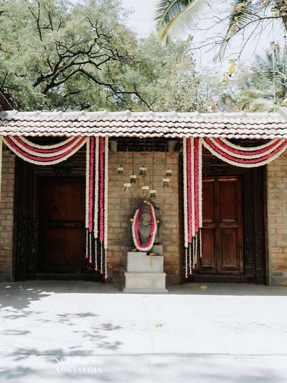 The entrance gates adorned with traditional red and white floral curtains, a classic and elegant decor choice for a heritage wedding.