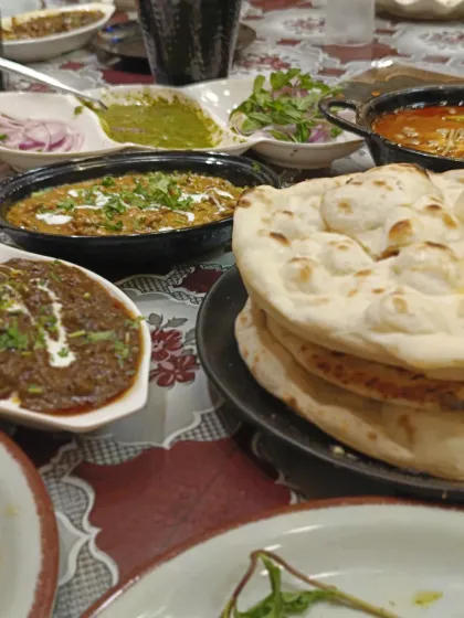 A beautiful spread of our Mughlai main courses. This table features a variety of our curries and gravies, served alongside a stack of fluffy, hot tandoori naan, ready for a family feast.