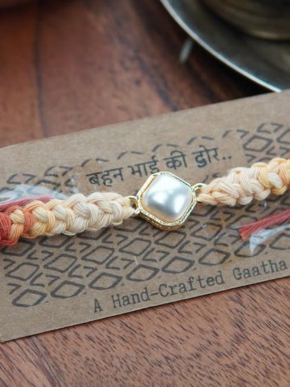 A close-up of the Kundan Rakhi on its packaging. The message reads 'Behen Bhai ki Dor' (the thread of a sister and brother).