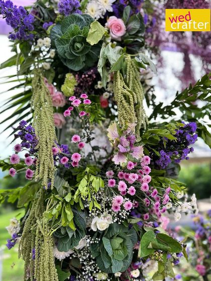 A close-up of the intricate floral work on the garden arch, showing a mix of lilac, lavender, and green foliage for a natural, soothing look.