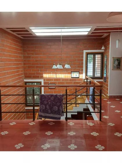 A view from the upper floor, looking down into the stairwell. The patterned red oxide floor adds a touch of traditional charm.