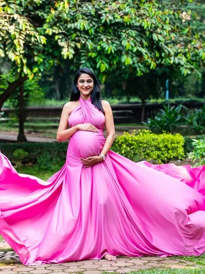 A stunning solo portrait of the mom-to-be in a flowing pink gown. The fabric seems to fly, creating a sense of freedom and joy.