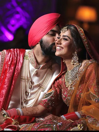 A sweet, intimate moment between the bride and groom. Her jewellery sparkles as he kisses her cheek.