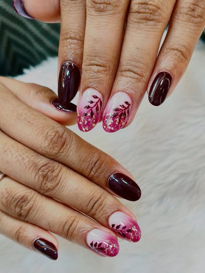 A beautiful fall-inspired design. This set features a mix of solid wine-colored nails and ombré accent nails with delicate leaf art and gold foil flakes.