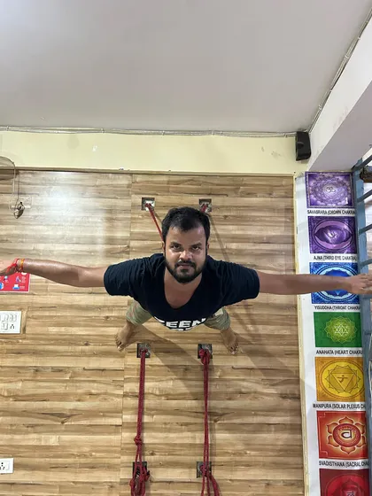 This top-down angle shows the full extension of the arms and the engagement of the back muscles in this rope-assisted pose. This practice is highly effective for correcting rounded shoulders and building a strong, upright posture.