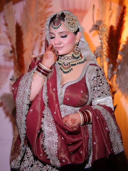 A shy, beautiful moment. This bride's maroon velvet lehenga is paired with soft, glowing makeup that enhances her natural elegance.