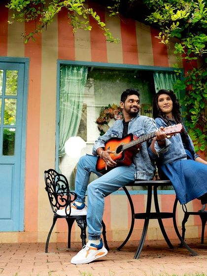 A couple serenades each other with a guitar in the same charming garden spot.