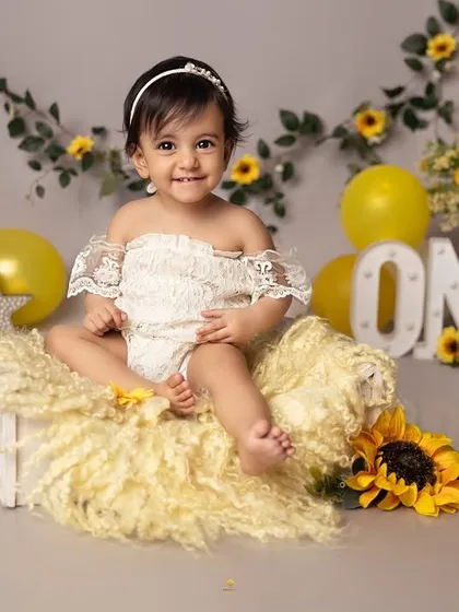 Sitting pretty among the sunflowers. This classic portrait from a first birthday session captures the calm before the cake-smashing storm, highlighting her sweet and gentle nature.