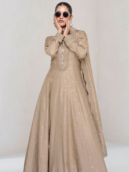 This beige premium silk gown is the definition of understated elegance. The delicate thread embroidery and sequins add a touch of sparkle, making it perfect for a reception or evening party.