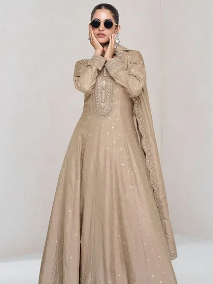 This beige premium silk gown is the definition of understated elegance. The delicate thread embroidery and sequins add a touch of sparkle, making it perfect for a reception or evening party.