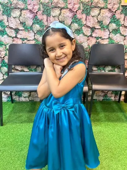 A smile that says it all. This little one is ready for a party in her bright blue satin dress, complete with a sparkling sequin collar and a sweet bow at the waist.