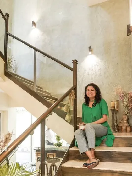 A shot of me sitting on the staircase from image 23, which features textured cement walls and a cozy bar nook underneath.