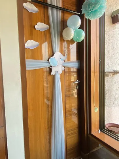 A charming and simple door decoration to welcome a baby boy home. We used light blue tulle wrapped around the door like a present, accented with a cute elephant cutout, paper clouds, and a small bunch of balloons.