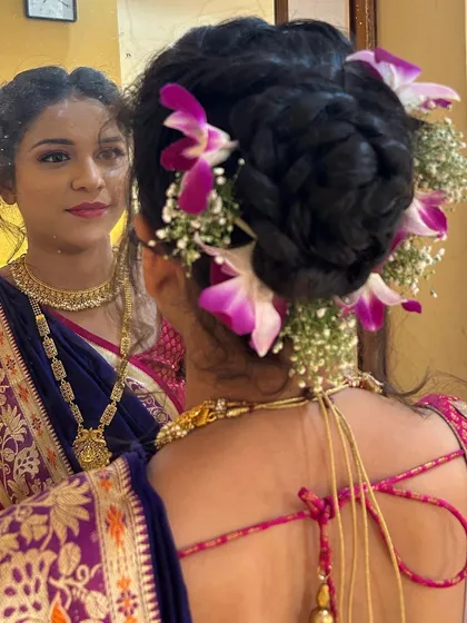 A mirror shot showing both the front and back of the look. This highlights the detailed floral hairstyle and how it complements the bride's reflection.