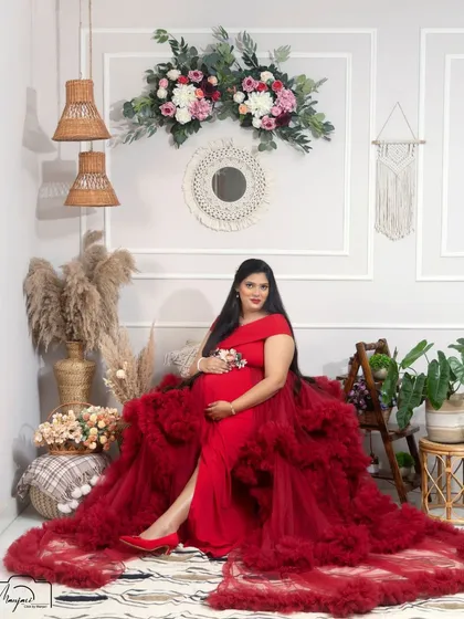 A full view of the stunning red gown in the boho corner. This portrait is all about glamour, confidence, and the power of motherhood.