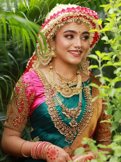 A candid moment of a bride with the Sharadha Jalli, her smile framed by lush greenery. This shot captures the happiness and beauty of the tradition.