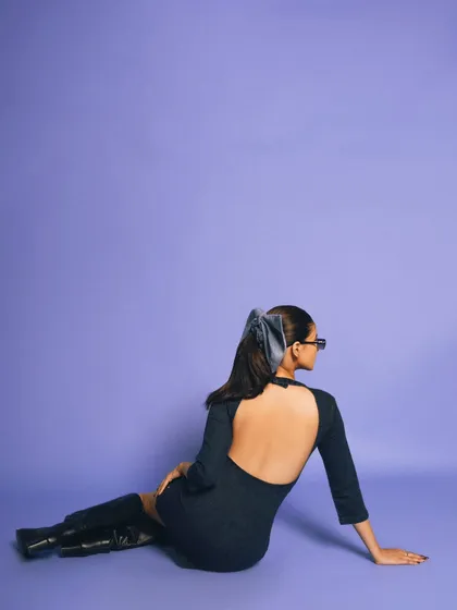 A shot for a denim brand, focusing on a backless dress. The clean lavender background and the model's pose create a chic and minimalist aesthetic.