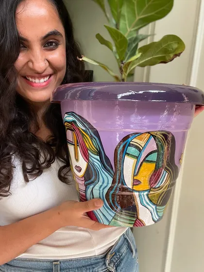 Me holding a large planter painted with my signature abstract face style.